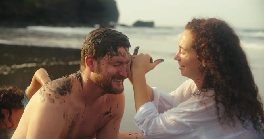 Sand is wiped on the mans face on the beach