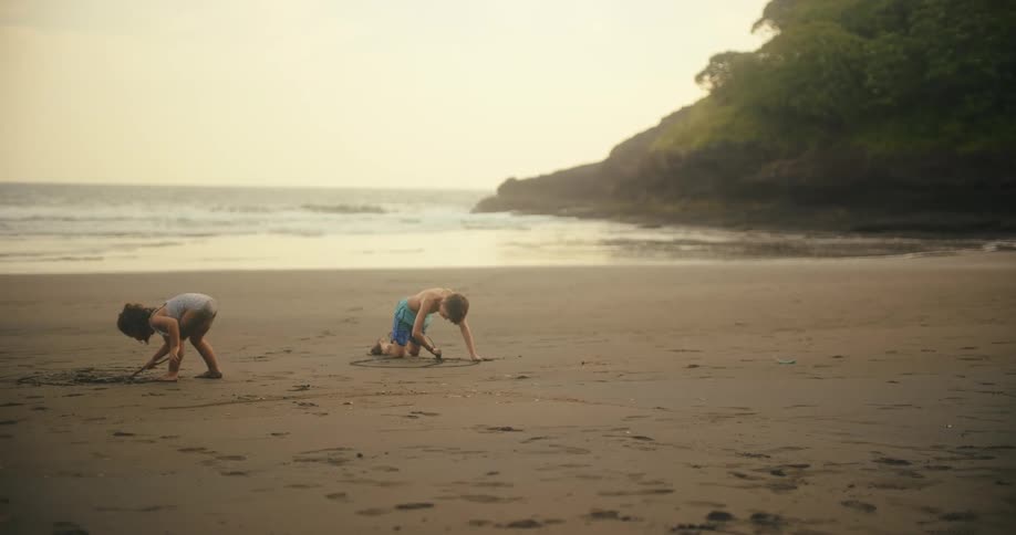 A young boy and girl are playing in the sand on a beach