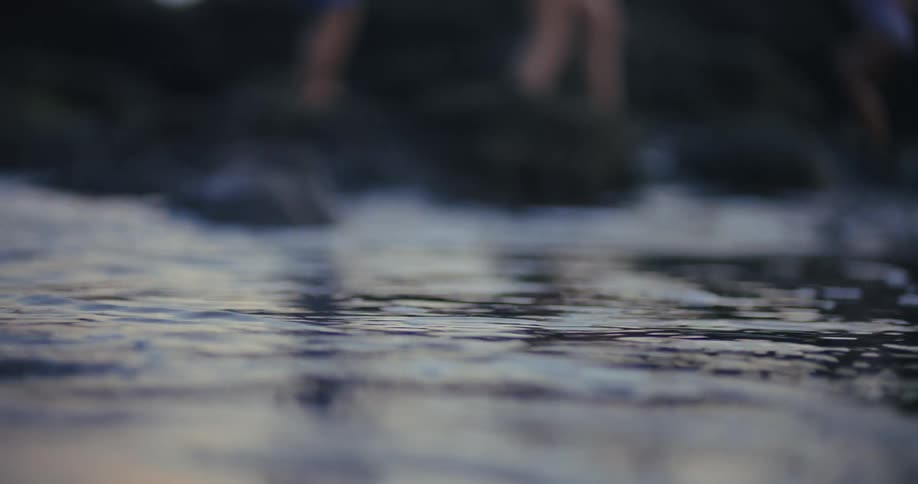 A family stands together on dark coastal rocks in swimsuits