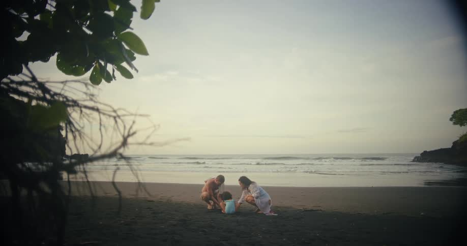 A happy family builds a sandcastle on a tropical beach