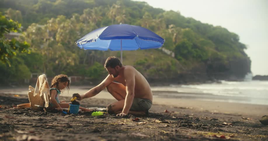 A father and daughter dig in the sand together