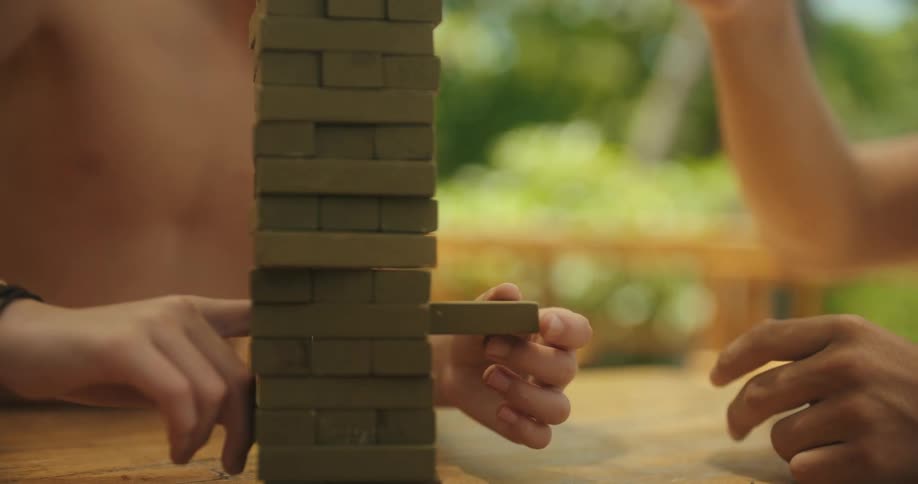 Family plays a wooden stacked game while outdoors on a summer day