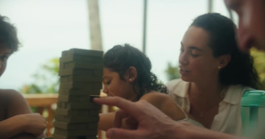 A happy family enjoys playing jenga on vacation outdoors