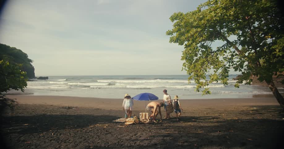 Family sets up chairs near an umbrella on the beach on a cloudy summer day