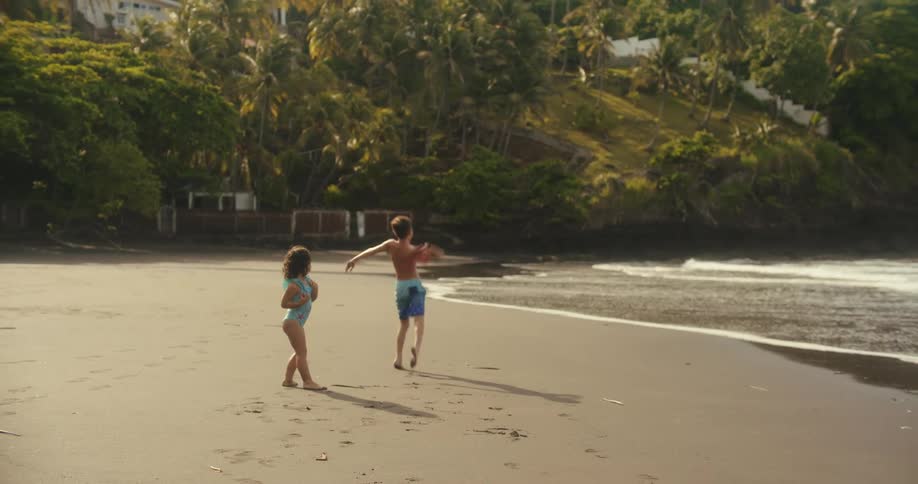 Two happy kids playing on the beach next to the ocean