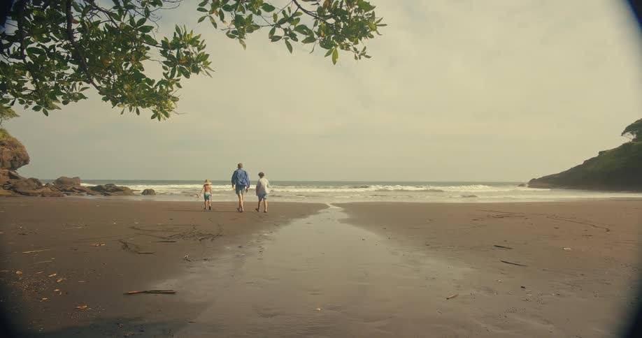A father and his two sons walk along a beach towards the ocean