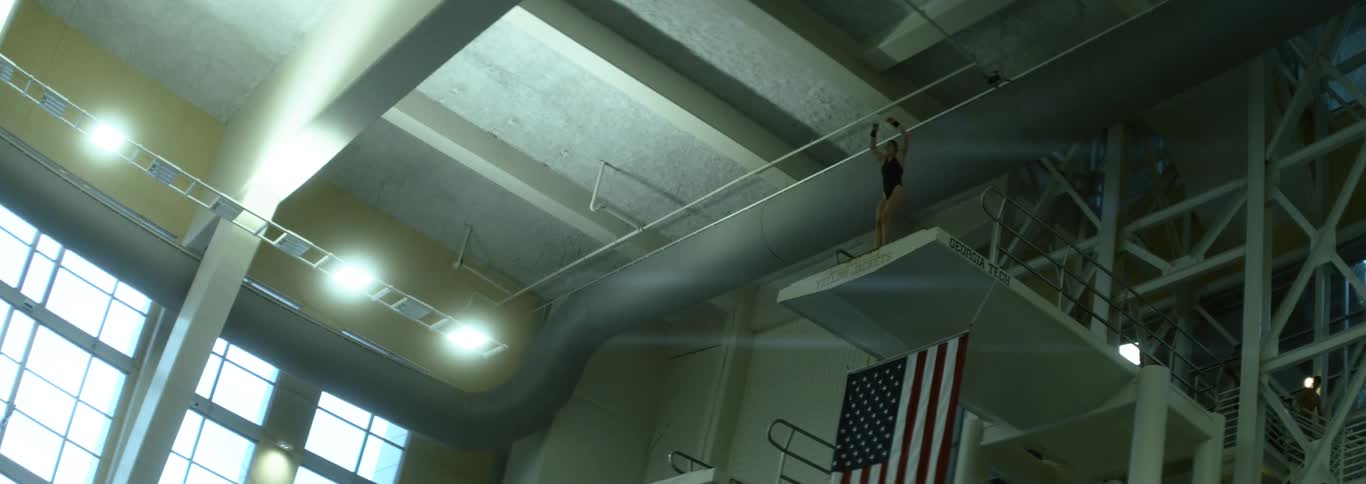 A woman preparing to jump from a diving board in a diving routine