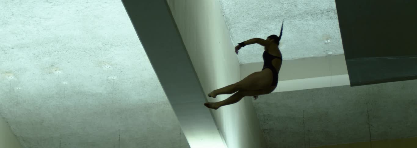 Female acrobat twisting in the air while falling indoors