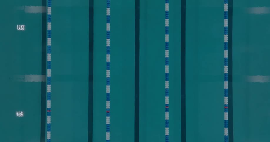 Aerial view of an olympic swimming pool with aligned blue and white lanes