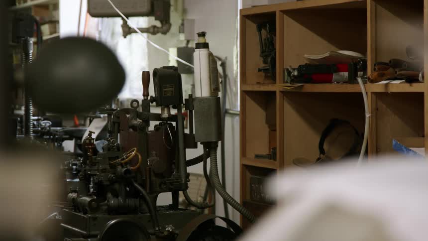 Parts and tools are located on shelves next to a vintage printing press