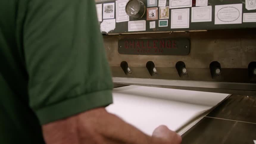 Person handles sheets of paper in front of an old machine