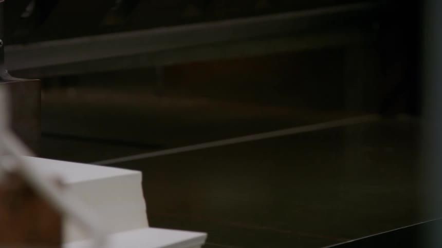 Close up of a man picking up a stack of fresh papers from a table top