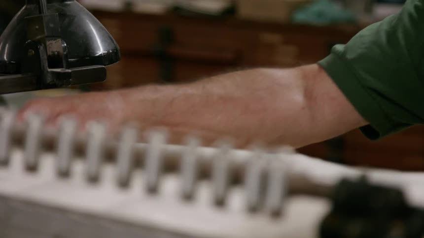Arm of a person operating a printing machine with a stack of aligned papers