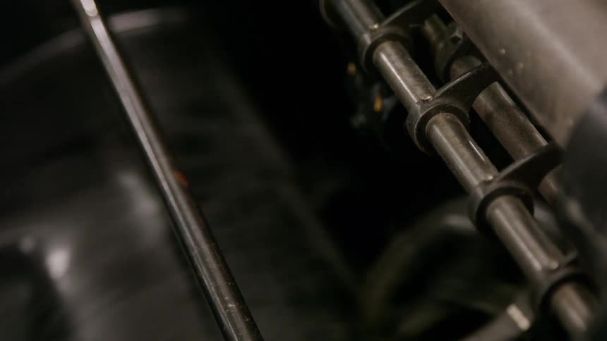 The video shows a closeup shot of a complex machine with a variety of levers and moving parts a sheet of paper is visible underneath the mechanism