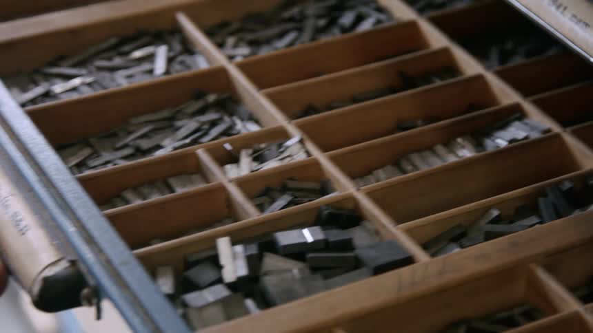Close up of a man closing a cabinet drawer filled with small metal bars