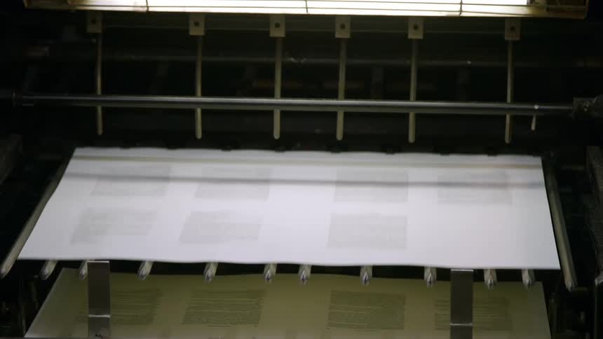An automated printing press outputs multiple sheets of paper