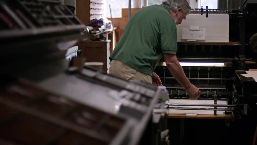 Man examines a large freshly printed document while working during the daytime
