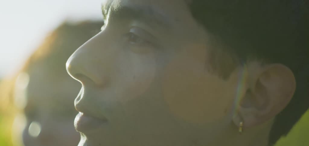 A face of two young adults looking to each other in an outdoor setting