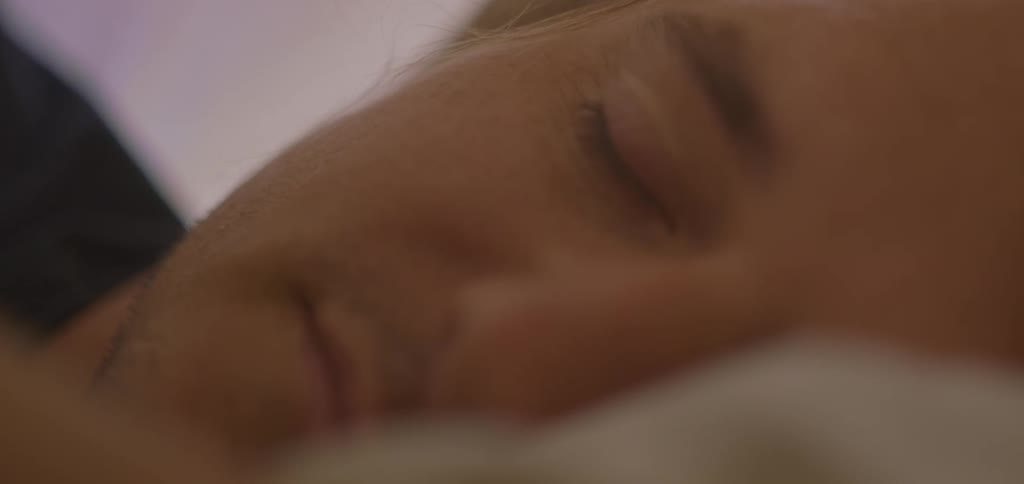 A middleaged man lies on his bed with his eyes closed fast asleep