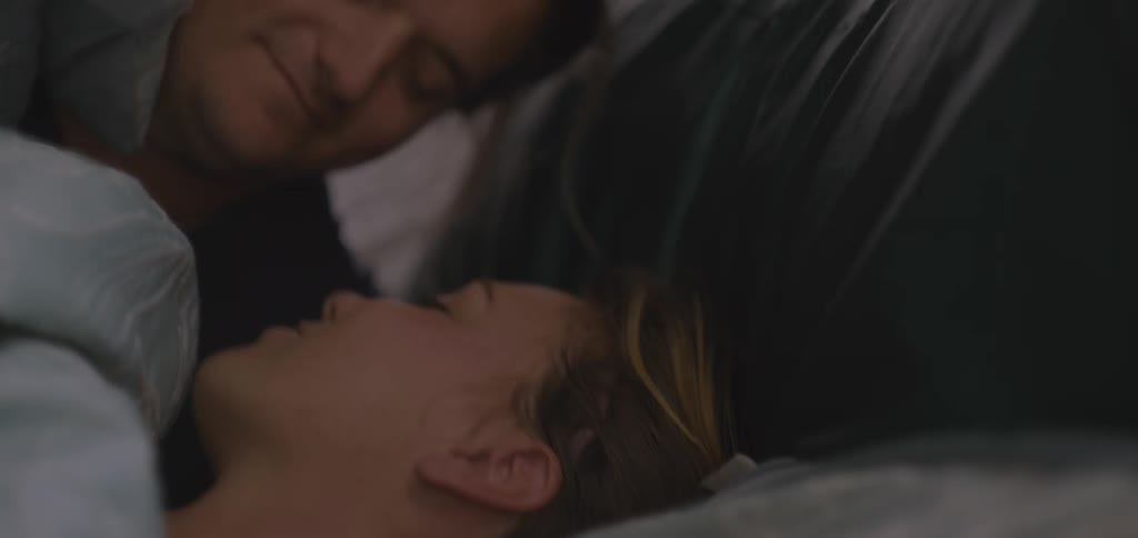 A couple a man and a woman hugging and covering themselves up to the head with a blanket in bed