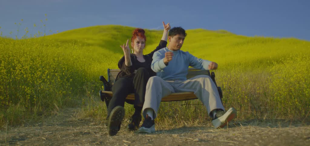 Two people are dancing while sitting on the bench near the flowers