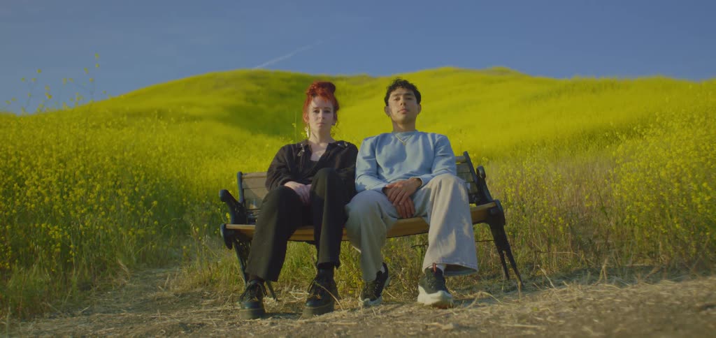 Couple sitting on a bench on grassy hillside in the countryside