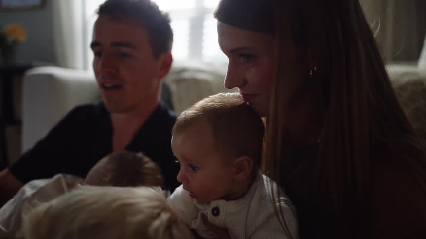 Family gathered at home with children on their parents laps