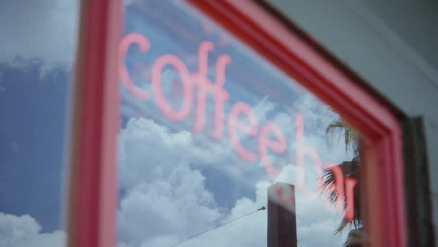A neon sign for a coffee bar in a window
