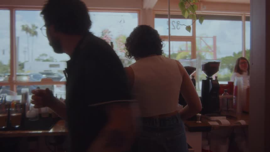 A barista prepares coffee as a customer waits in the shop
