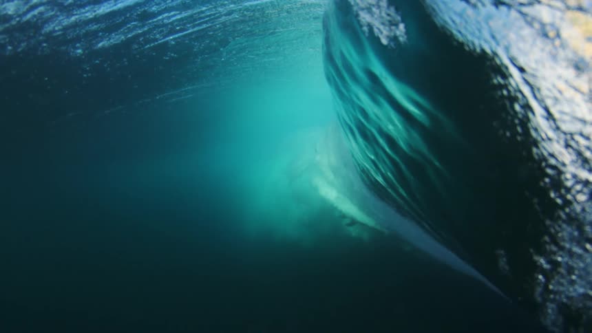 A man surfs on a large ocean wave on the beach