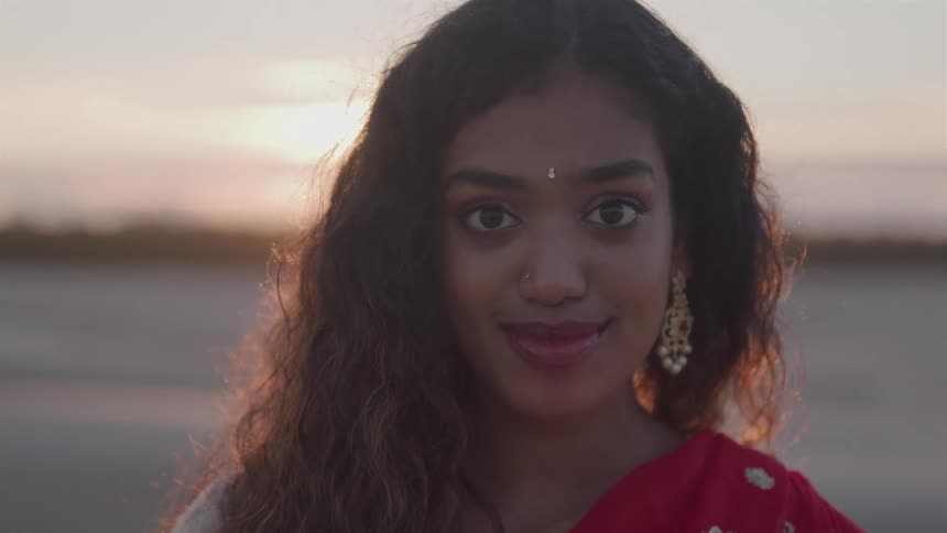 A closeup of an indian woman smiling while posing at sunset