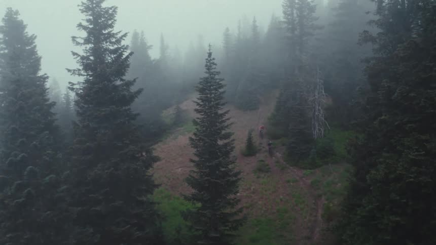 The two mountain bikers ride down the foggy mountain