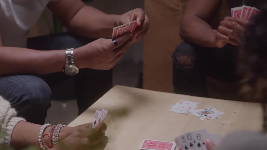 Friends gathered around coffee table playing a card game