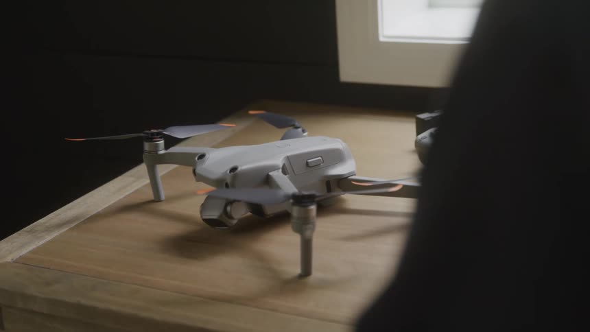 Close up of a drone with its controller placed on a wooden surface in a room during daytime