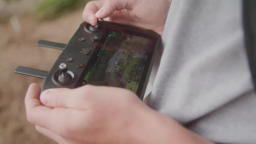 The man is holding a controller for a drone with many buttons on it