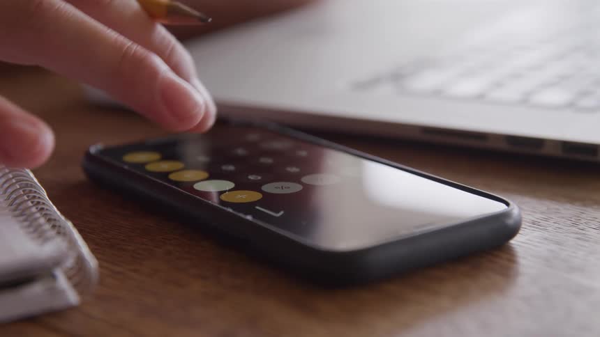 Person uses the calculator app on a smartphone placed on the table