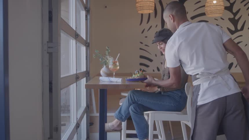 Male restaurant server bringing female customer her order