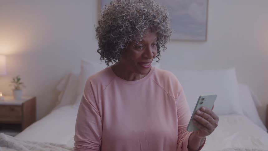 Smiling woman waves during a video call on her phone