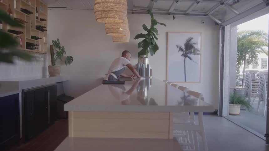 Person arranges objects behind a counter in a modern bright bar