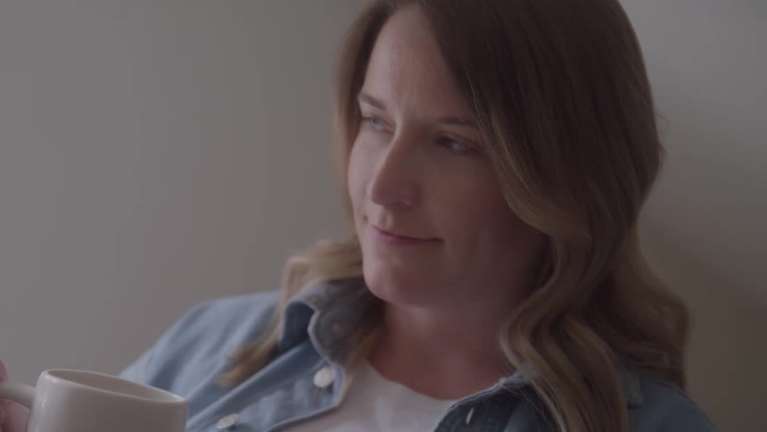 The woman is smiling while drinking coffee