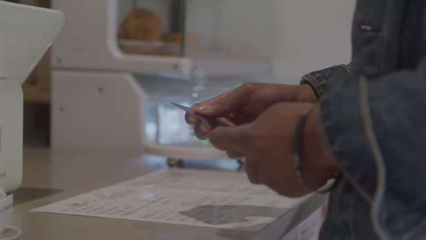 The customer holds his credit card at the counter to pay
