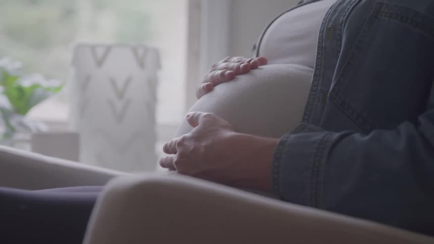 A persons hands rub her pregnant belly