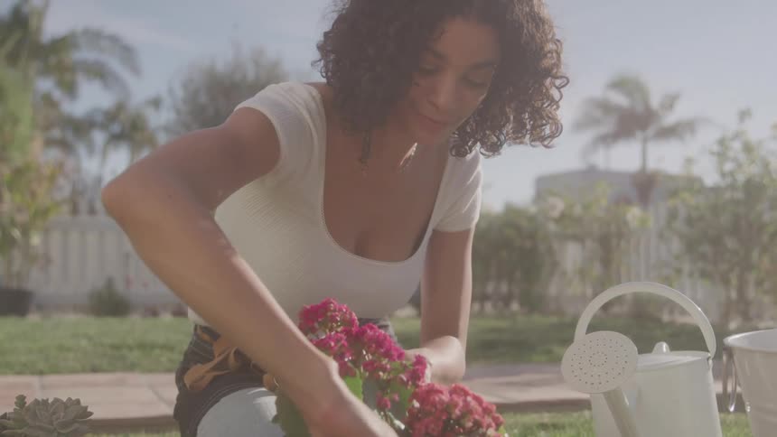 A woman plants flowers in the garden on a sunny day