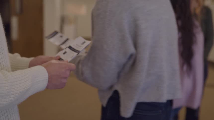 A person hands out id badges at the hallway entrance