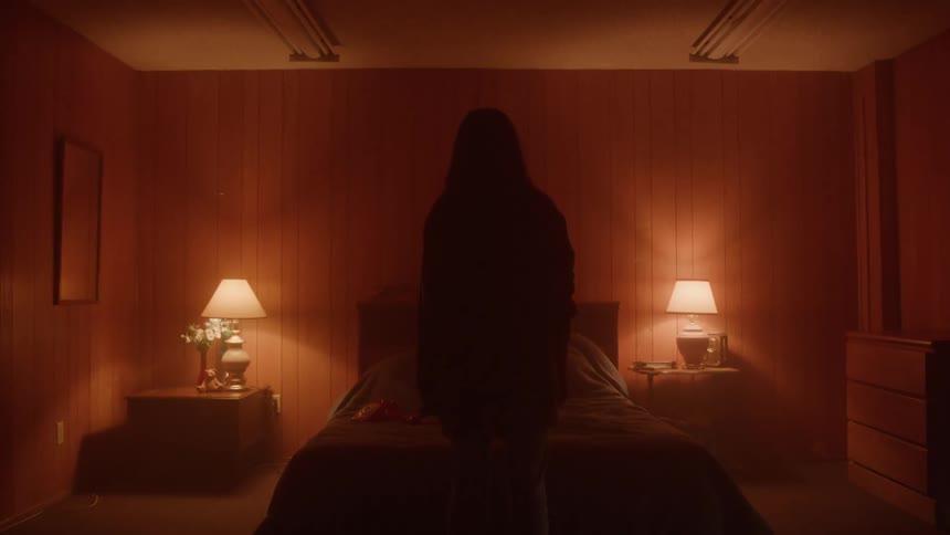 The person stands at the foot of the bed