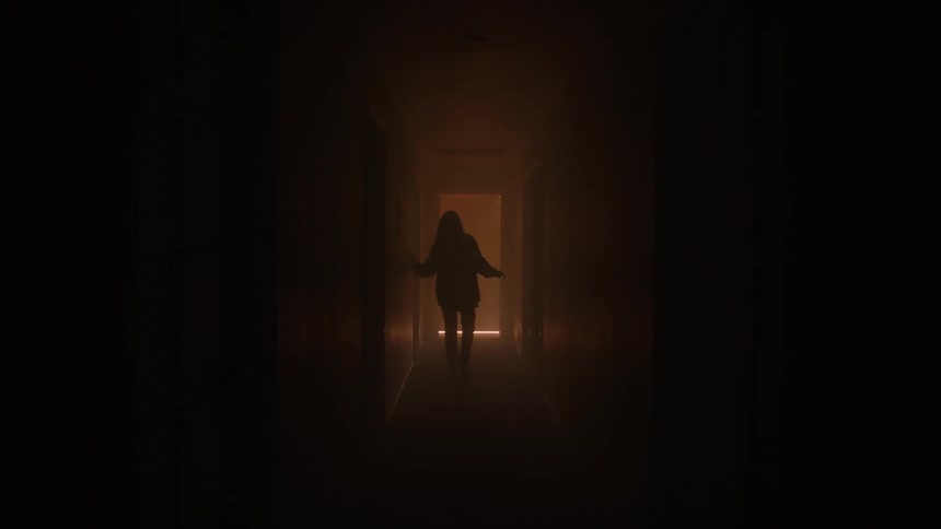 Silhouette of a young woman walking through a dark corridor in a building