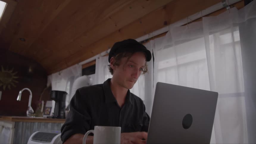 Man works on a laptop while sitting on the kitchen table