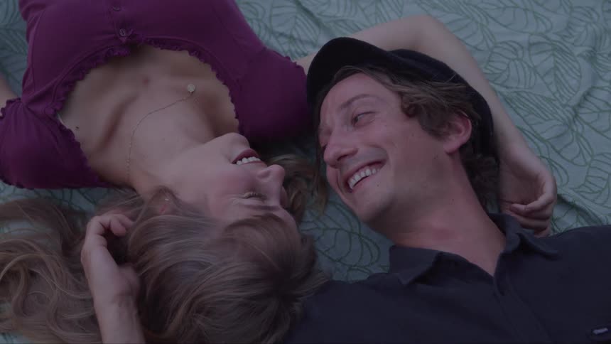 Couple lying on a blanket smiles while looking at each other