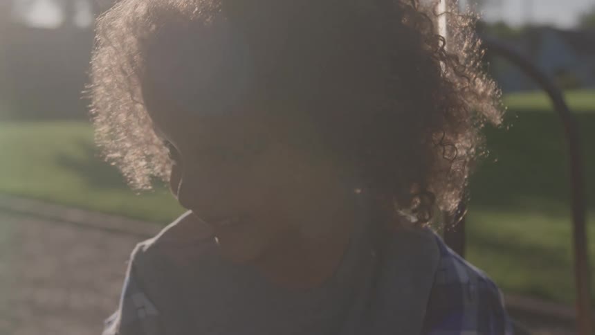 A young girl smiles as an adult spins her around on playground equipment