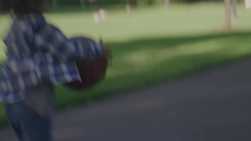 Child plays basketball dribbling the ball on an outdoor court